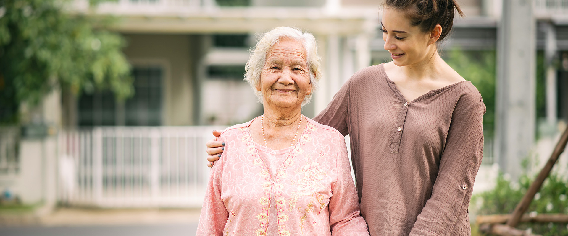 young woman holding older woman outside a home - New Perspective Careers Assisted Living Careers