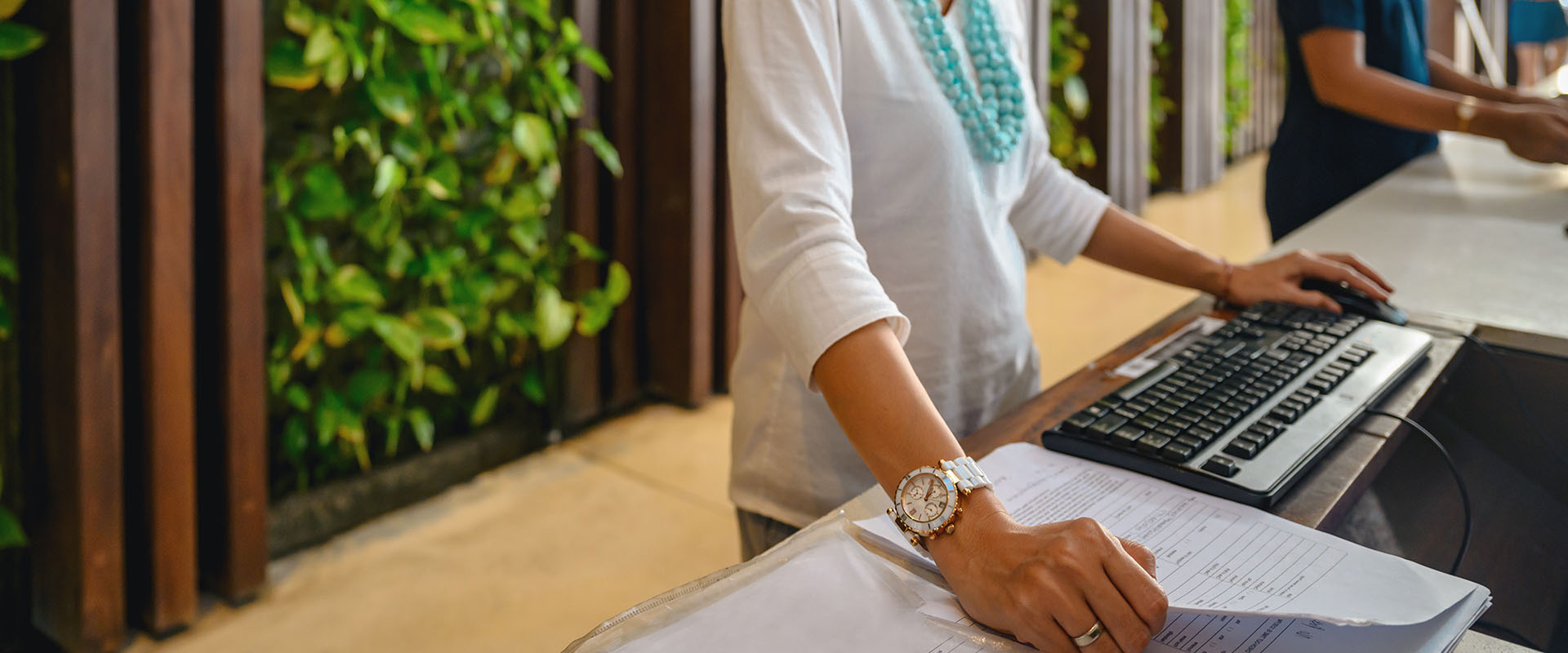 front desk employee working on paperwork at a computer - New Perspective Careers Assisted Living Careers