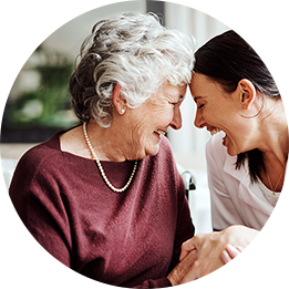 younger woman and older woman laughing with their heads pressed together - New Perspective Careers Assisted Living Careers