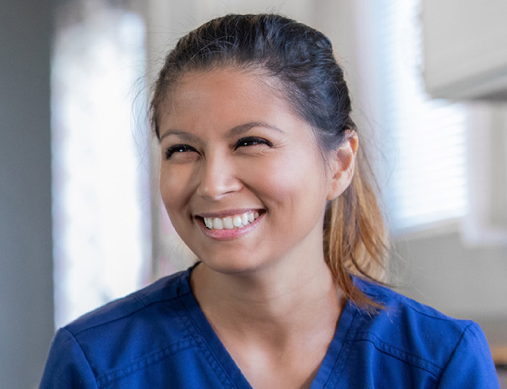 smiling woman wearing royal blue scrub top - New Perspective Careers Assisted Living Careers