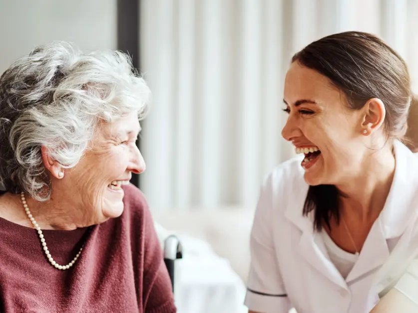 elderly woman laughing with caretaker - New Perspective Careers Assisted Living Careers