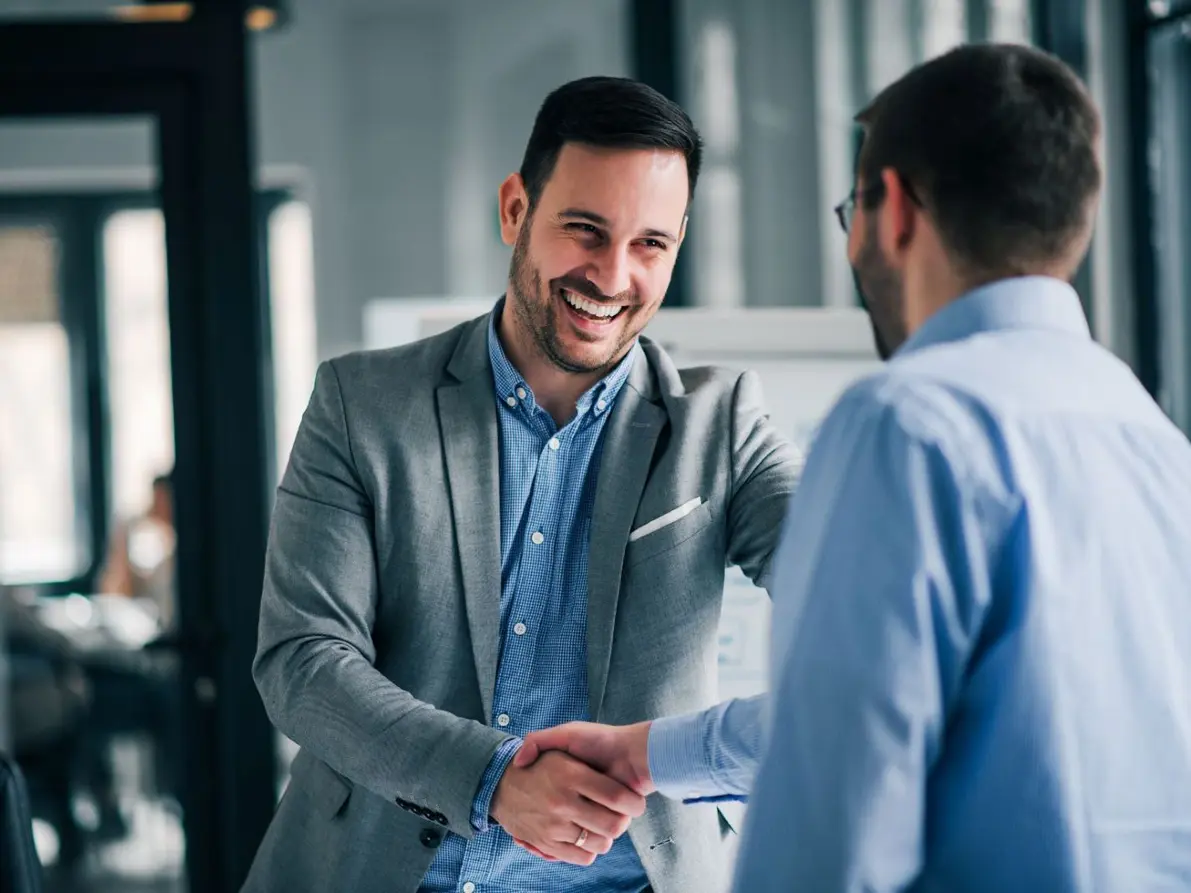 man smiling while shaking hands with another man - New Perspective Careers Assisted Living Careers