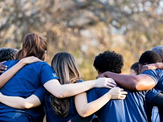 backside of a group of people with hands around one another - New Perspective Careers Assisted Living Careers