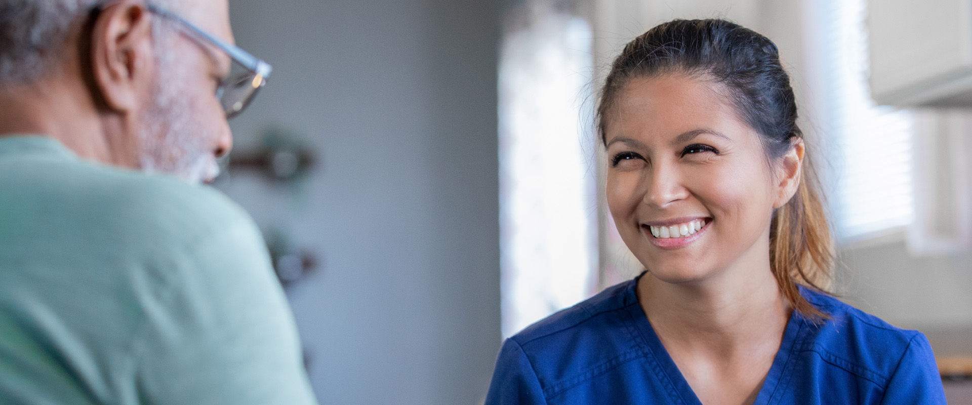 woman working with an elderly man while smiling - New Perspective Careers Assisted Living Careers