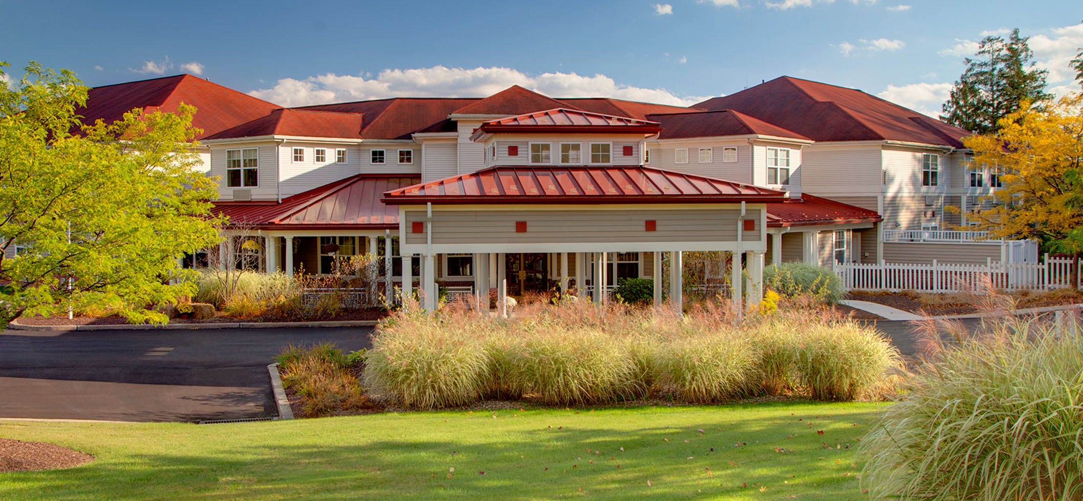 exterior of Richland Woods facility with white columns and red metal roof - New Perspective Careers Assisted Living Careers