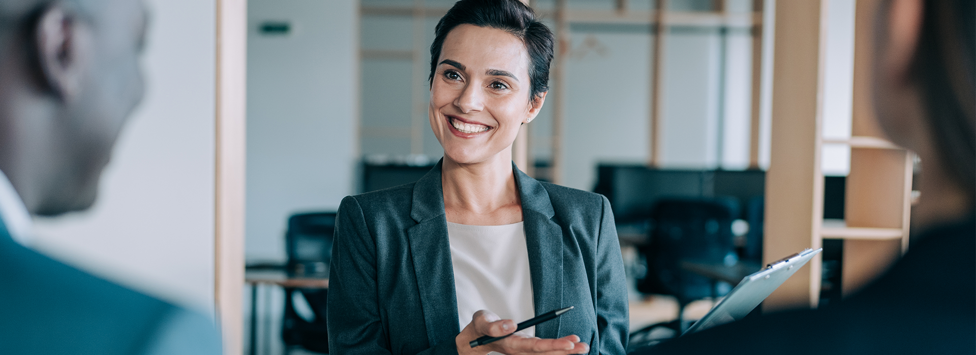 woman in a grey blazer smiling with a clipboard - New Perspective Careers Assisted Living Careers