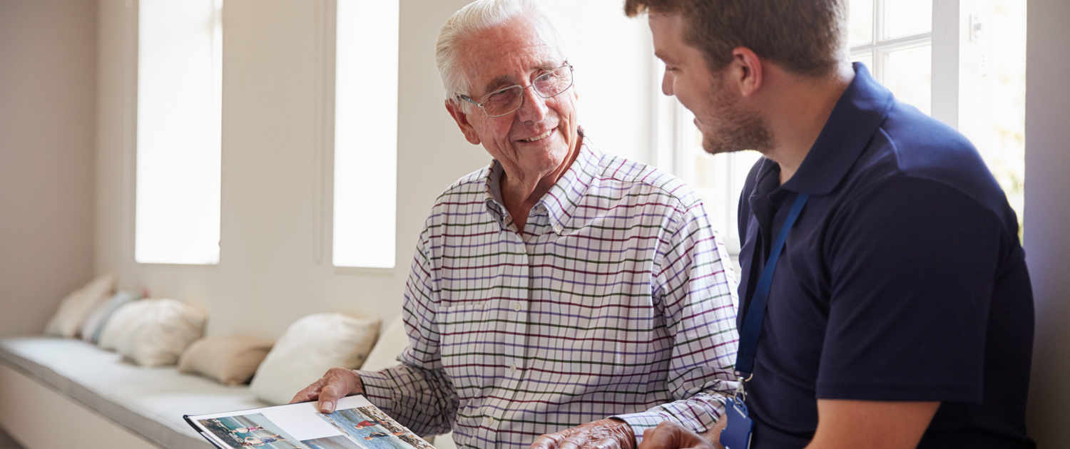 elderly man and employee looking through photo album - New Perspective Careers Assisted Living Careers