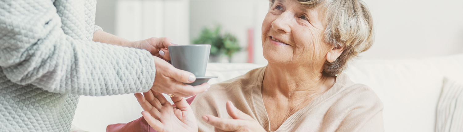 elderly woman grabbing coffee mug - New Perspective Careers Assisted Living Careers