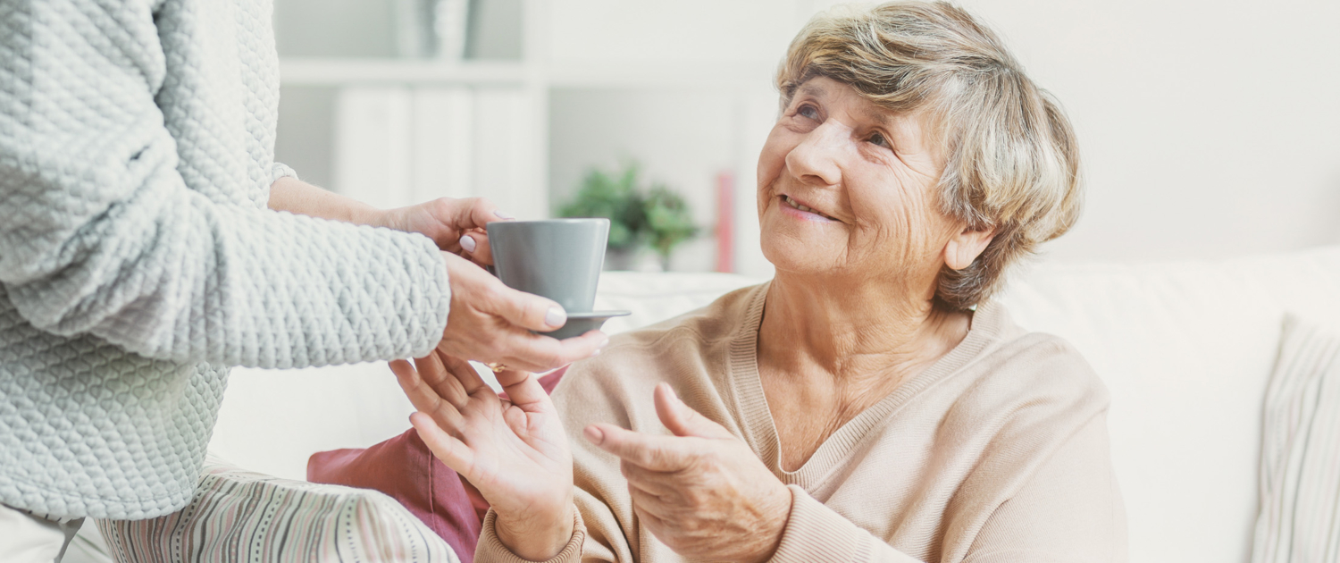 elderly woman grabbing coffee mug - New Perspective Careers Assisted Living Careers