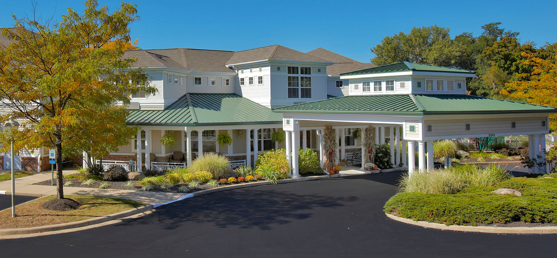 exterior of West Lake Woods facility with white columns and green metal roof - New Perspective Careers Assisted Living Careers